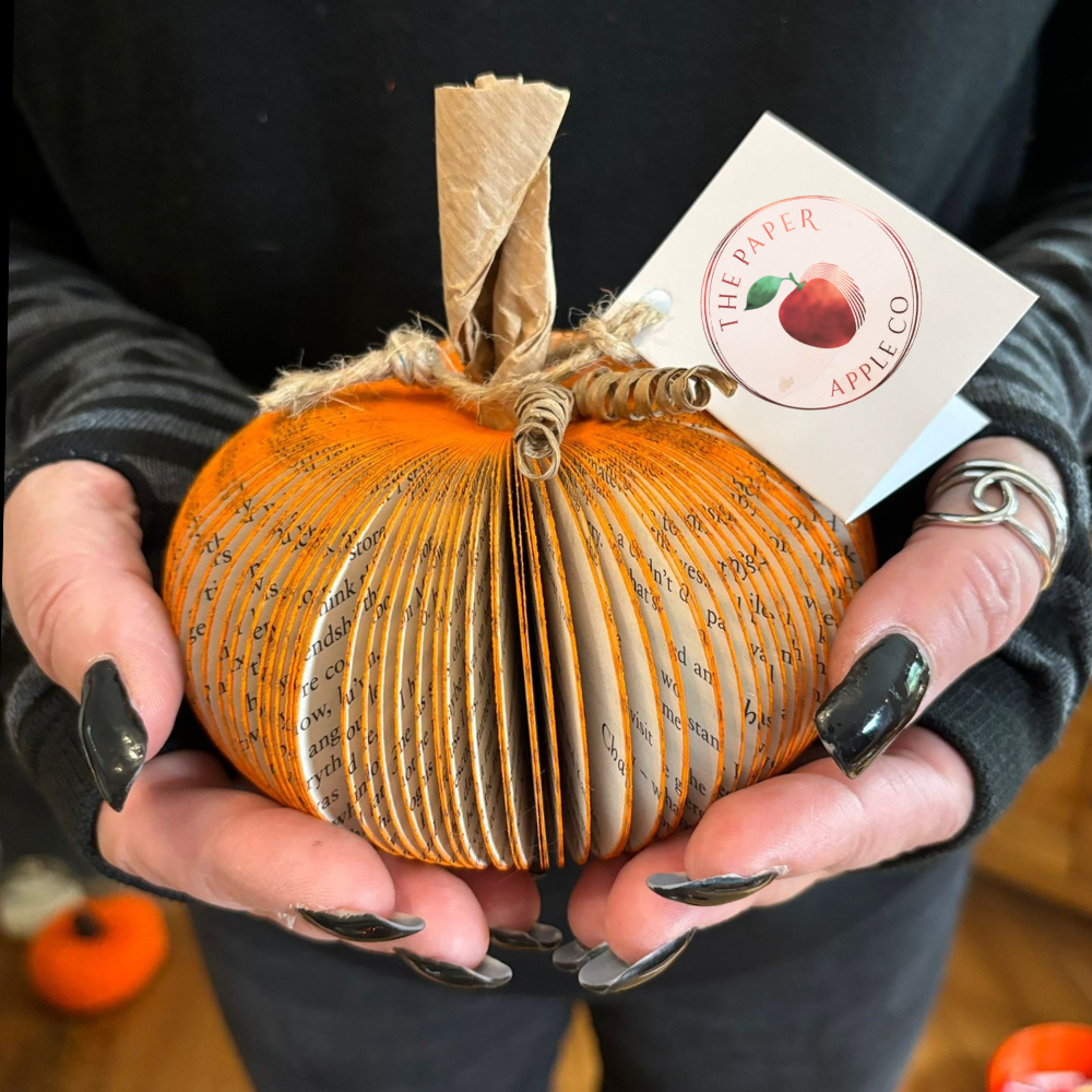 Handmade book pumpkin held in hands against a black background, as featured in Mamas & Papas
