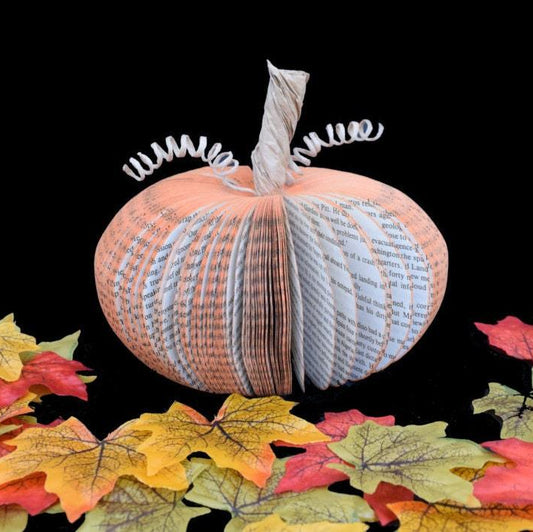 Medium book page pumpkin held in hands to show size
