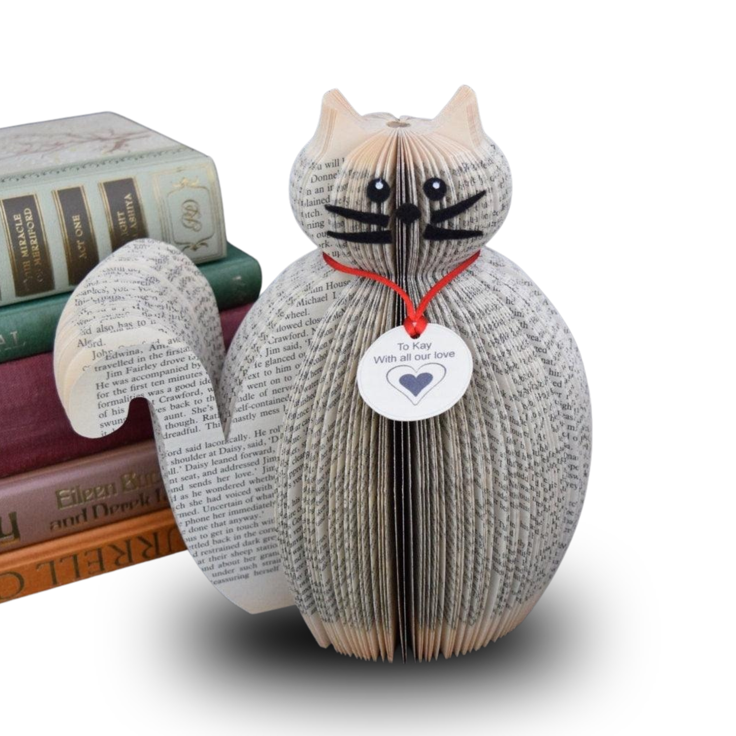 Handmade cat sculpture from book pages displayed with stacked books