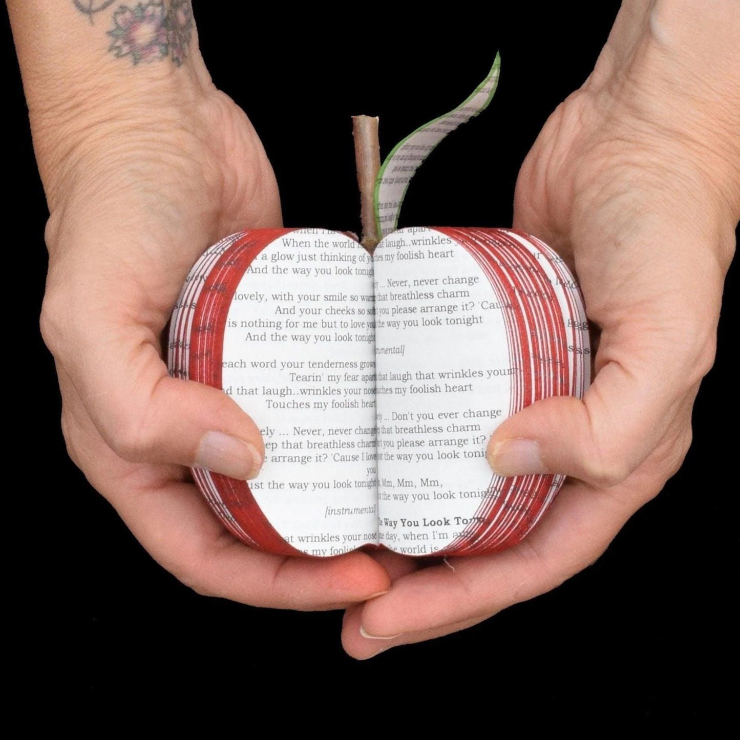 Handmade personalised song lyric apple held open showing custom printed words inside.