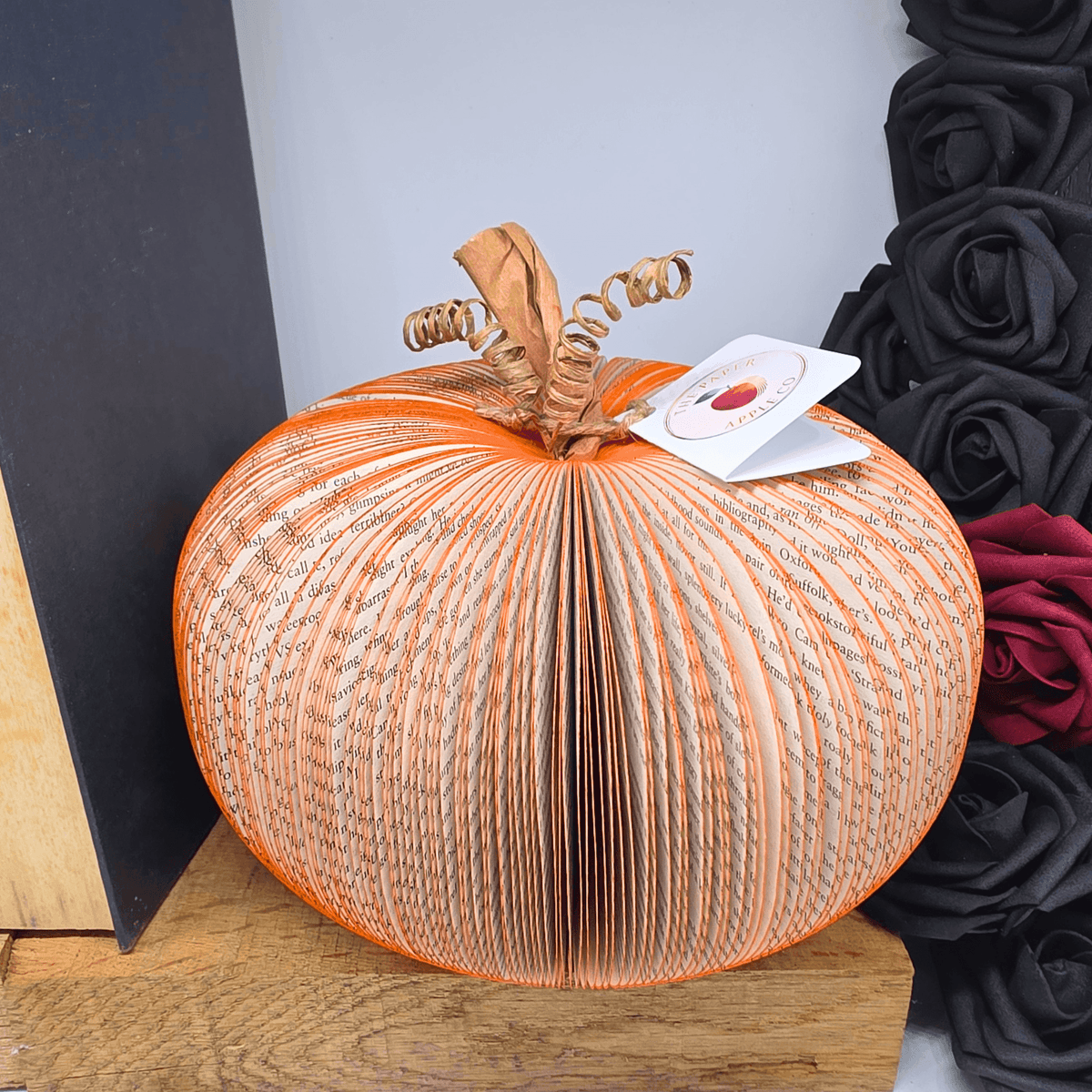 Large handmade book pumpkin displayed with autumn floral decor