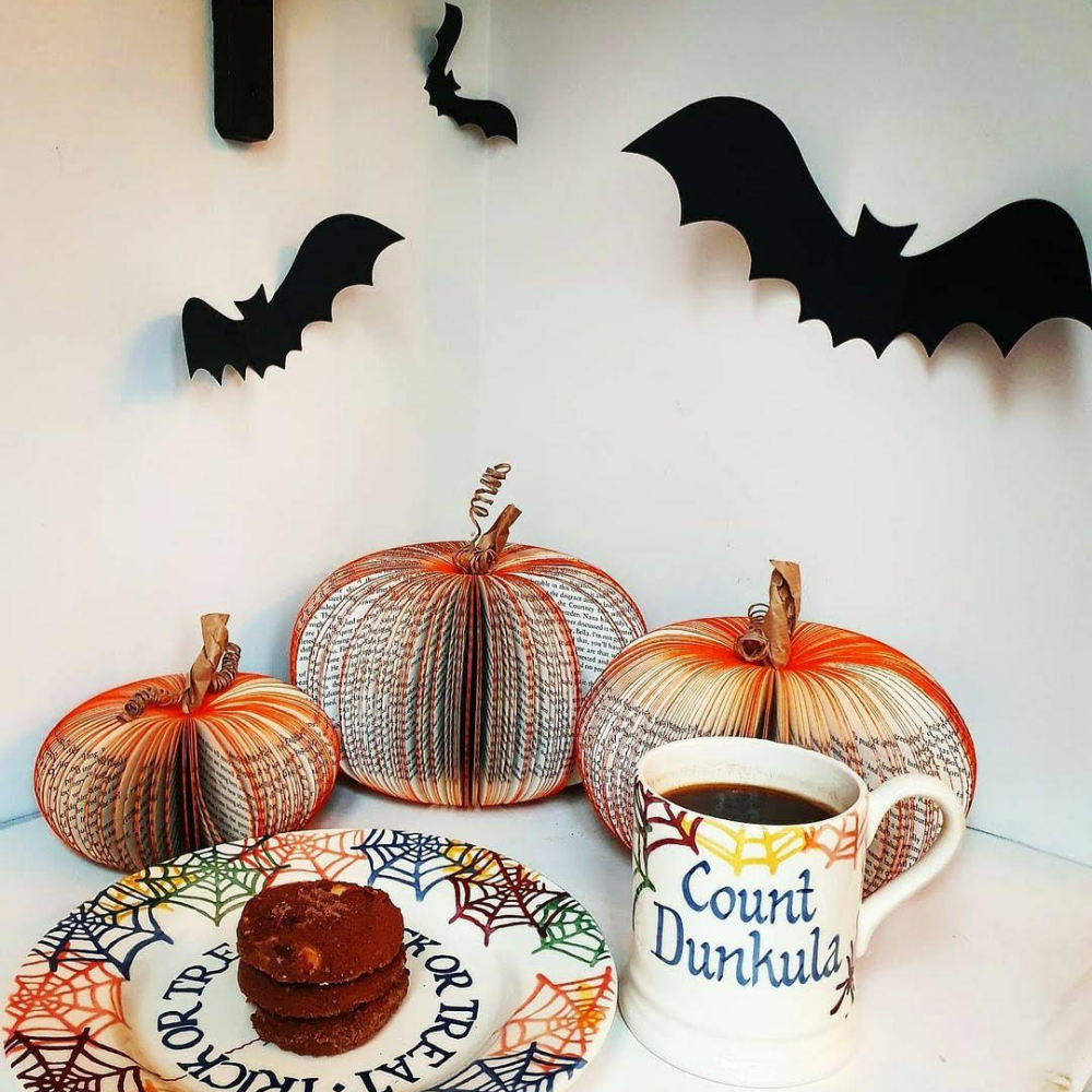 Set of three handmade book pumpkins displayed with paper bat Halloween decorations