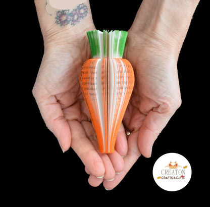 Handmade book page carrot sculpture held in hands to show size