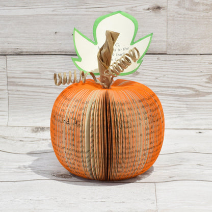 Handmade book page pumpkin held in hands to show size