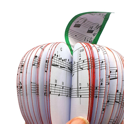 Music book apple held in hands to show size, handmade paper anniversary gift